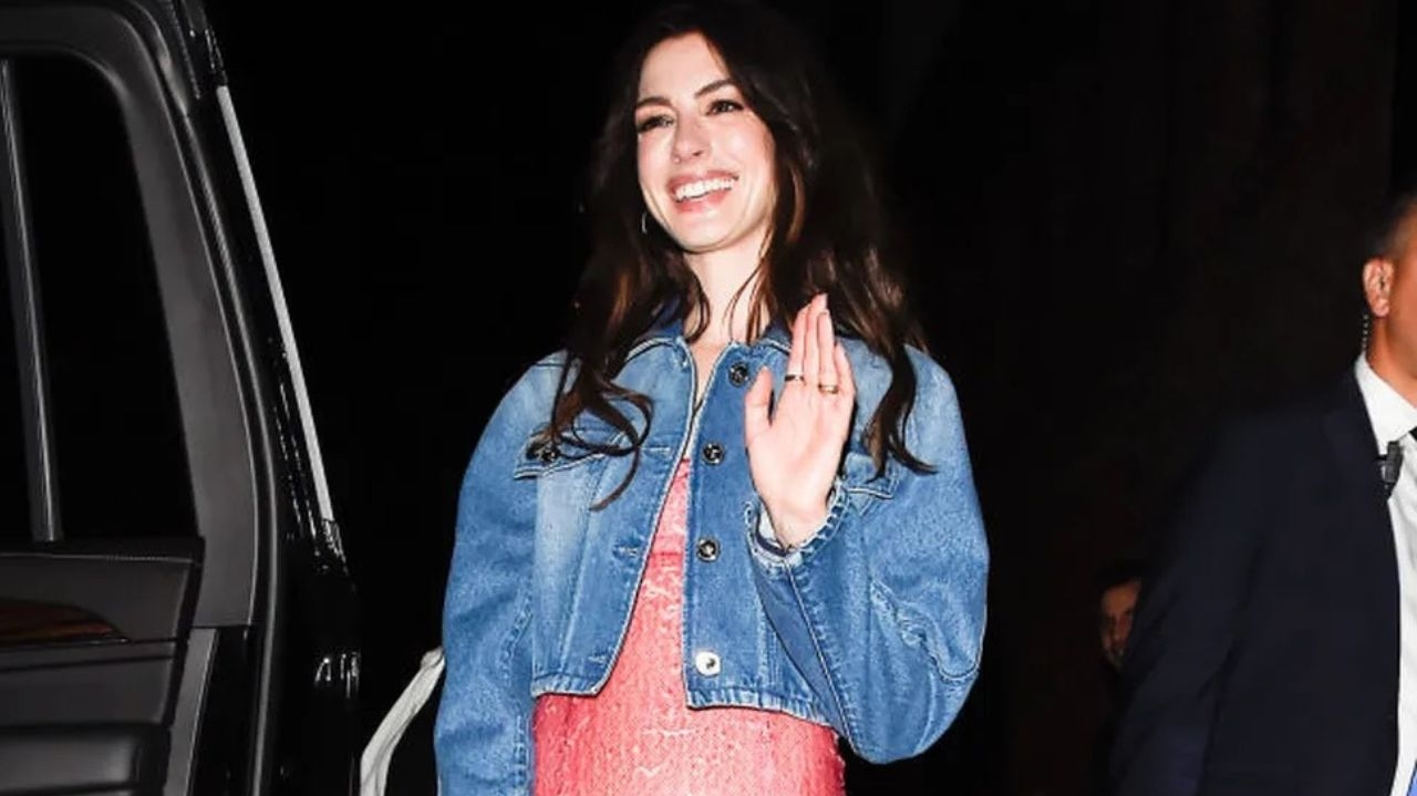 Anne Hathaway combina jaqueta jeans e vestido social em ato de versatilidade