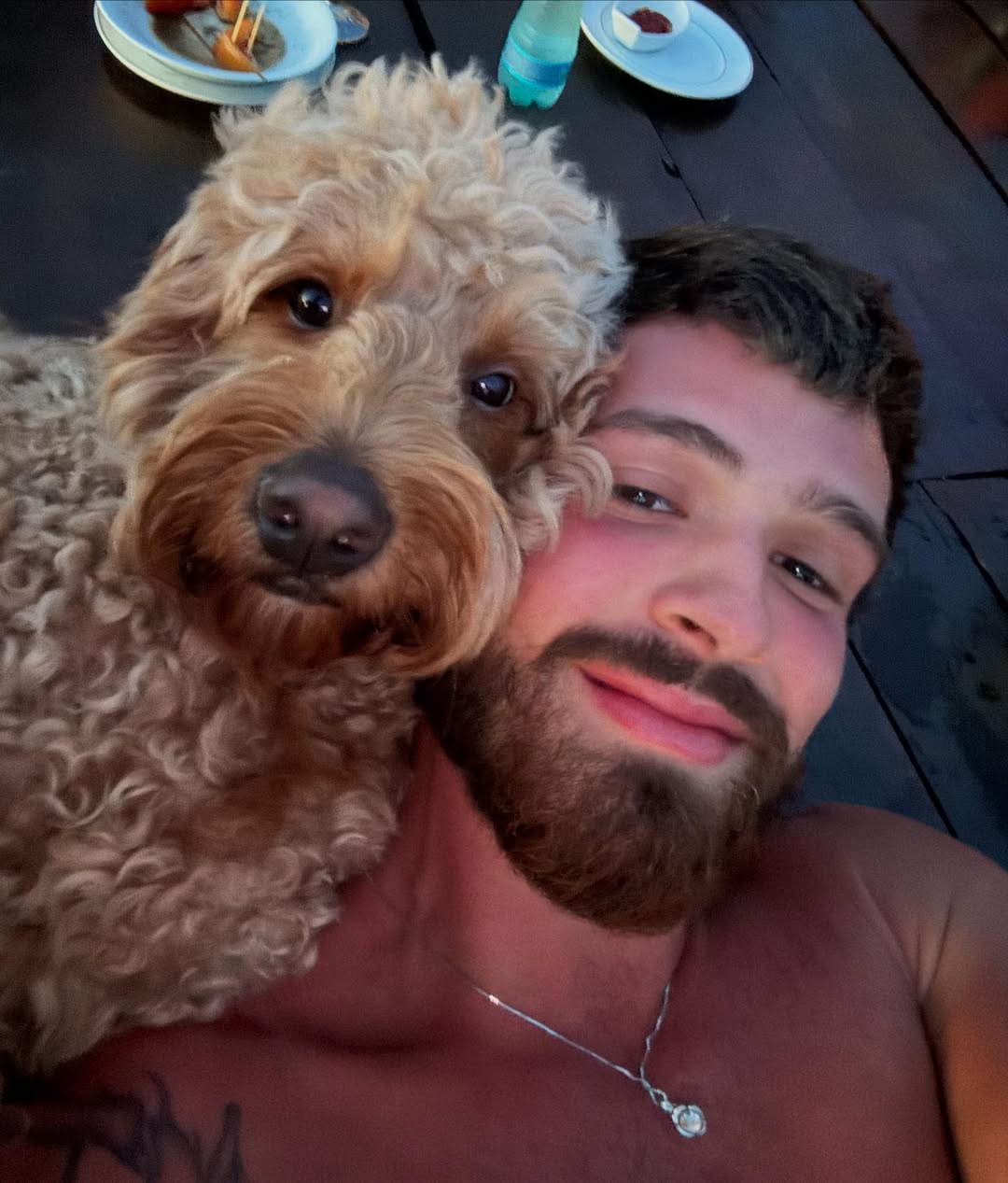 João Guilherme aparece em uma selfie ao lado de uma cadelinha de pelo encaracolado, ambos próximos ao rosto, em um momento descontraído