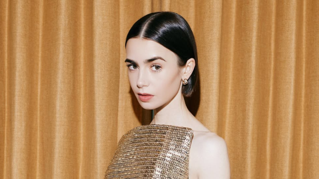 Lily Collins surge com look dourado da grife Carolina Herrera
